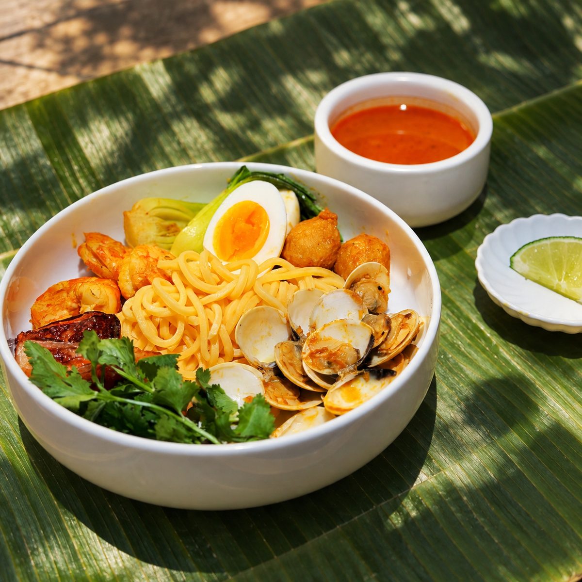 Laksa with shrimp, mussels, egg and tofu puffs on banana leaf